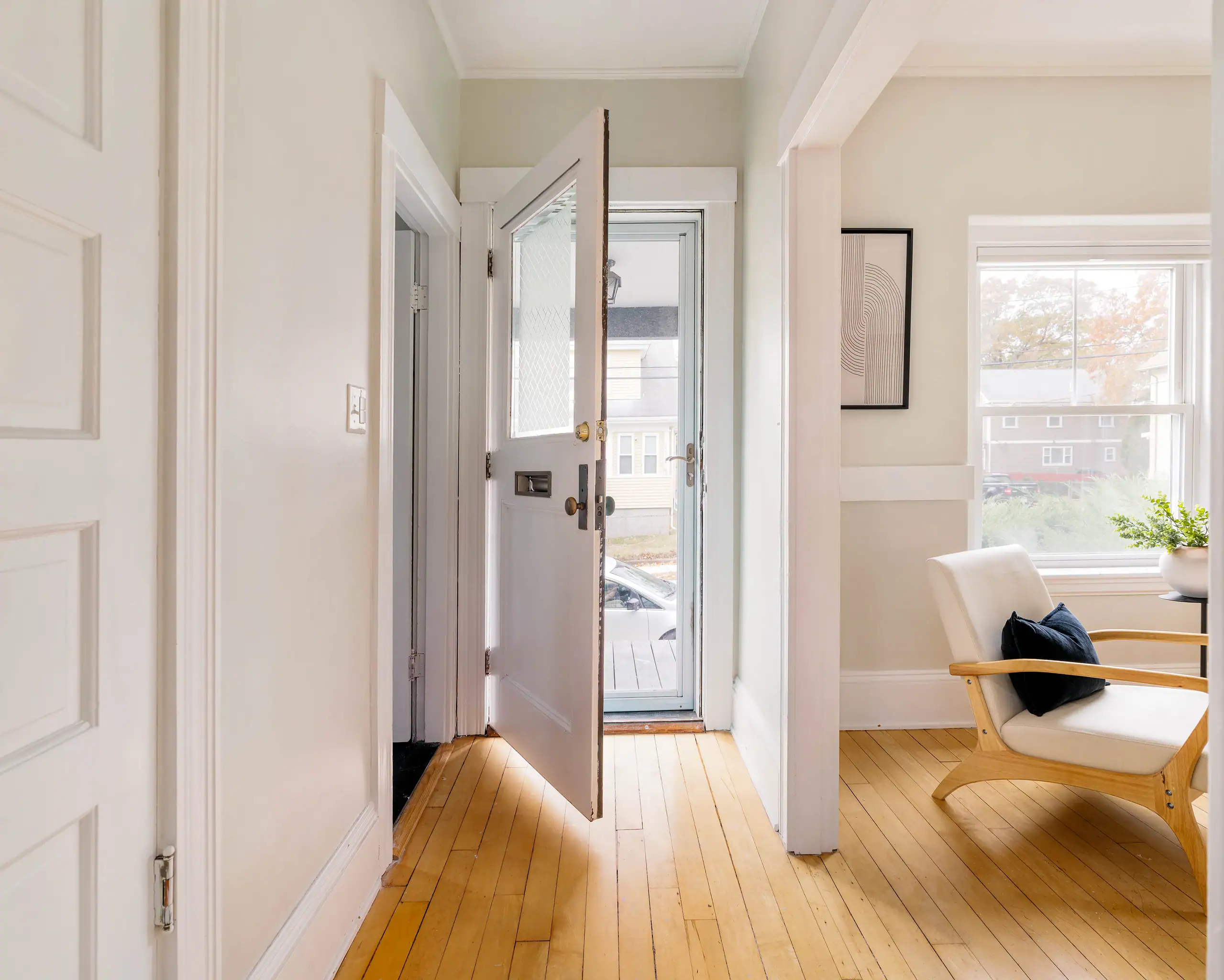 Bright hallway with hardwood floors and neutral walls, natural light from window, Boston home