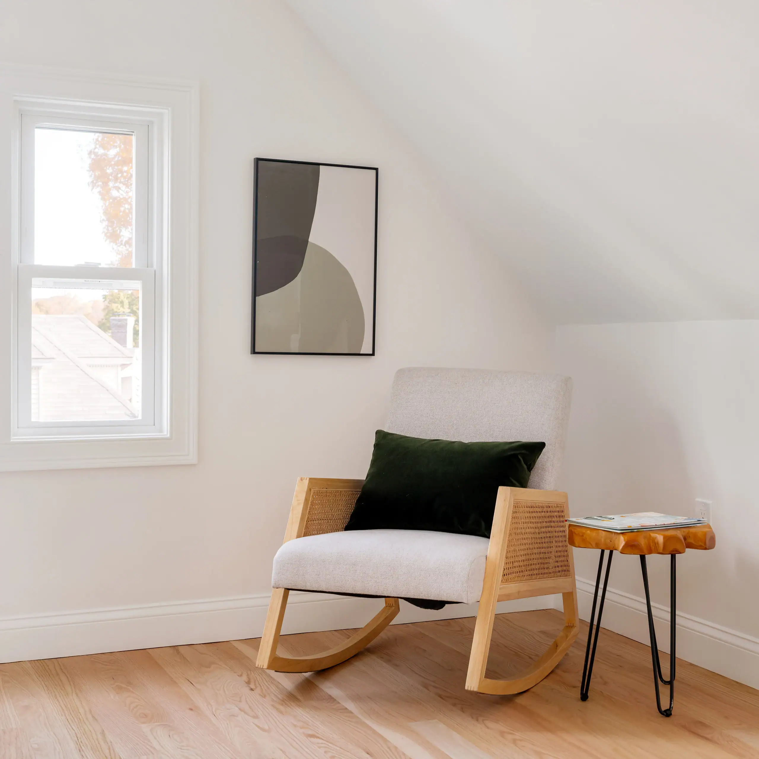 Modern living room with rocking chair and natural light overlooking residential street in Boston